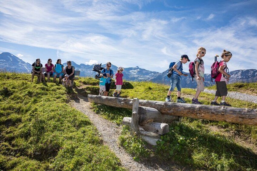 A group of hikers on a mountain trail with a wooden bridge and a clear sky. 1