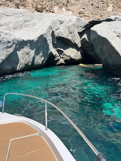 A boat near a rocky coastline with clear turquoise water. 1