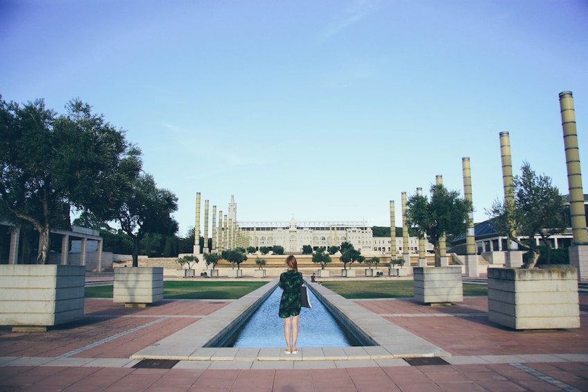A person standing in a reflective pool with a large industrial building in the background. 4