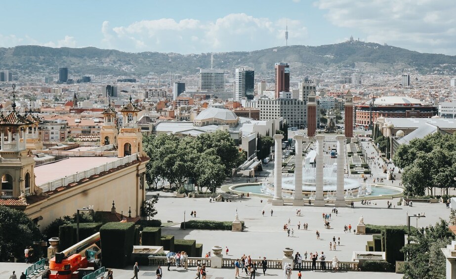 A city square with fountains, historic buildings, and a distant mountain range. 3