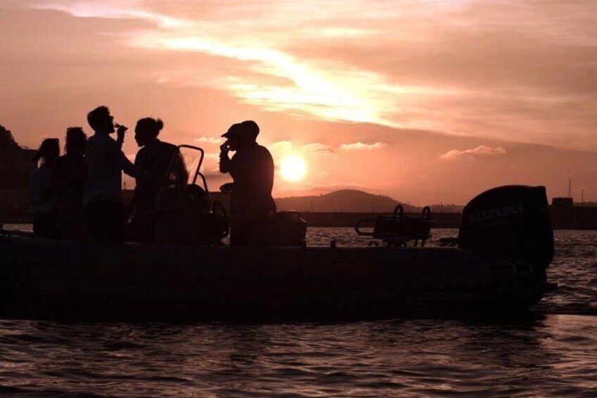 A sunset over water with people on a boat. 2