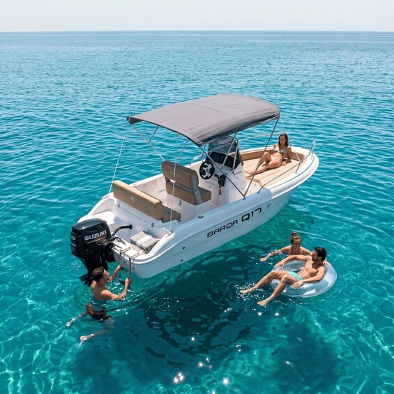 A white motorboat with a canopy, named BARQA Q17, on clear turquoise water. 3
