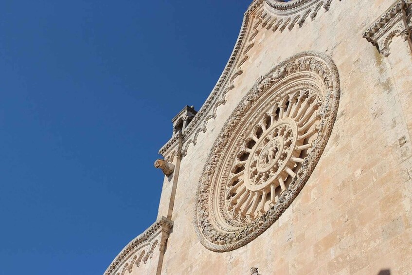 A detailed stone facade with a large circular window and ornate carvings. 4