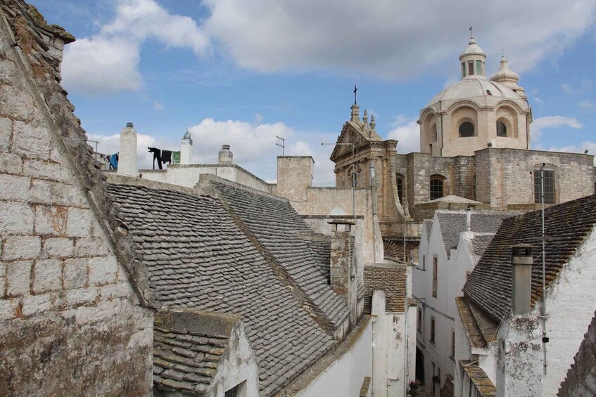 A historic town with stone buildings, a prominent church with a dome, and a narrow street. 2