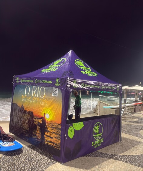 A purple Sunrise Rio Sup tent with a sunset mural, a QR code, and contact information. 5
