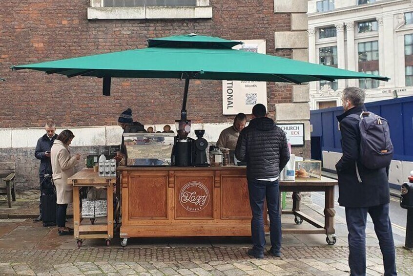 A wooden coffee cart with a green umbrella, a sign reading 'Tional,' and a logo that says 'Lofty Coffee.' 5