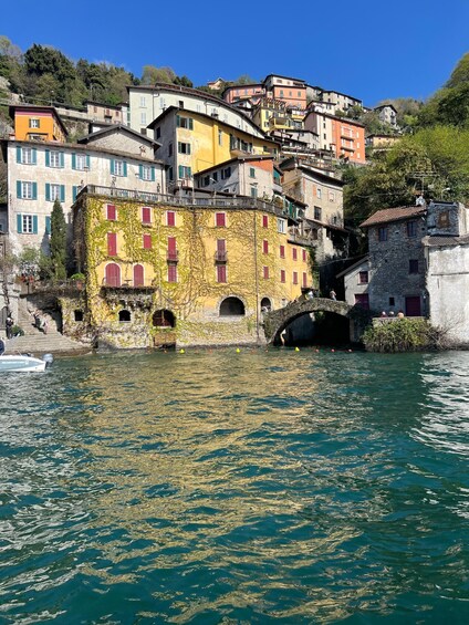A waterfront town with colorful buildings, a stone bridge, and a boat in the water. 1