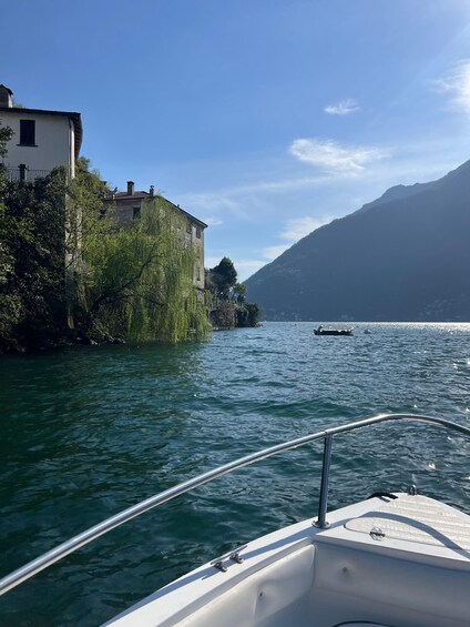 A boat on a calm lake with a building on the shore and mountains in the background. 4