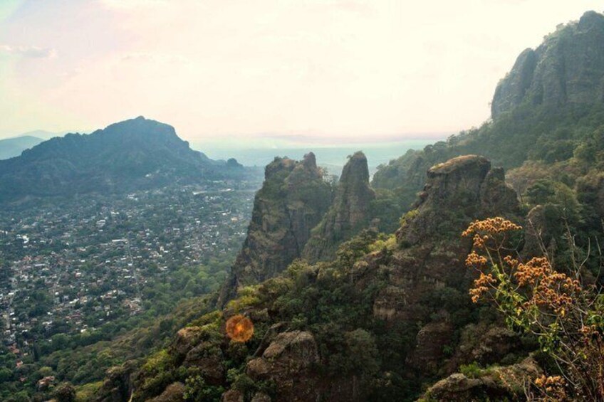 A mountainous landscape with a town in the valley, rocky outcrops, and dense greenery. 2