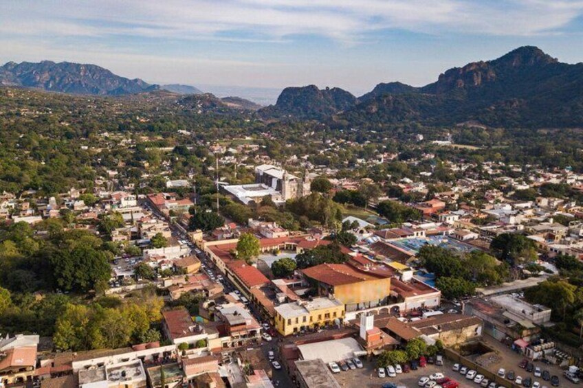 A town with a prominent church, a mountain range in the background, and a mix of residential and commercial buildings. 5