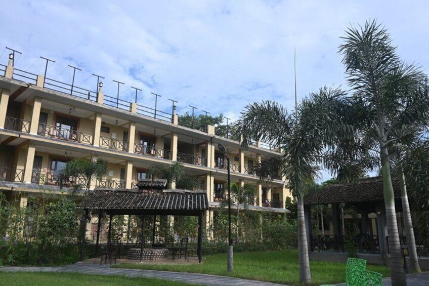 A multi-story building with balconies, a covered seating area, and palm trees. 4