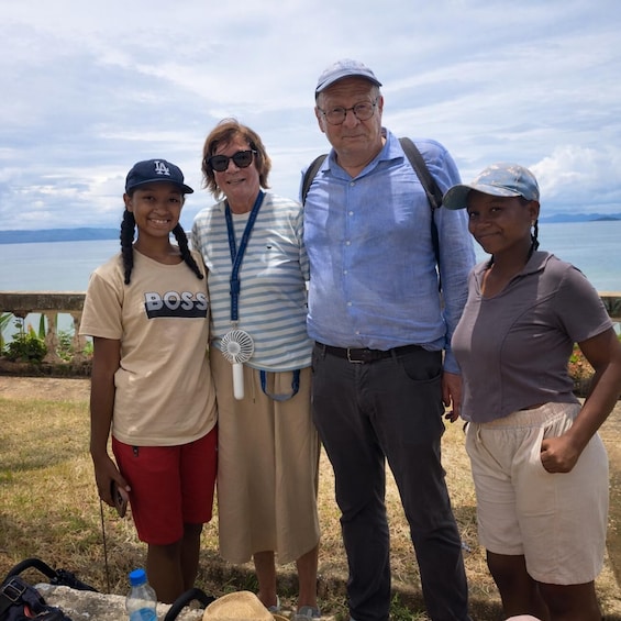 Four people standing outdoors with a body of water and mountains in the background. 5