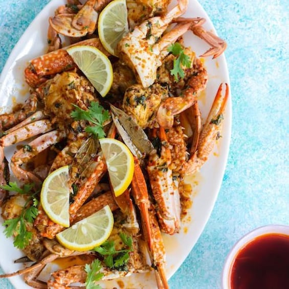 A plate of cooked crabs garnished with lemon slices and herbs. 4