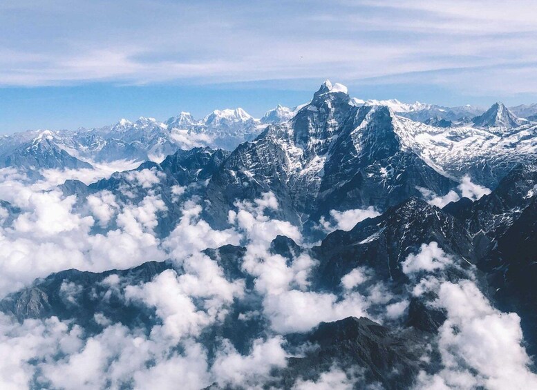 A mountain range with snow-capped peaks and clouds below. 4