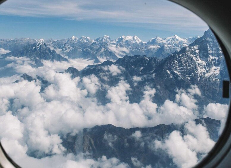 A mountain range with snow-capped peaks and clouds below. 5