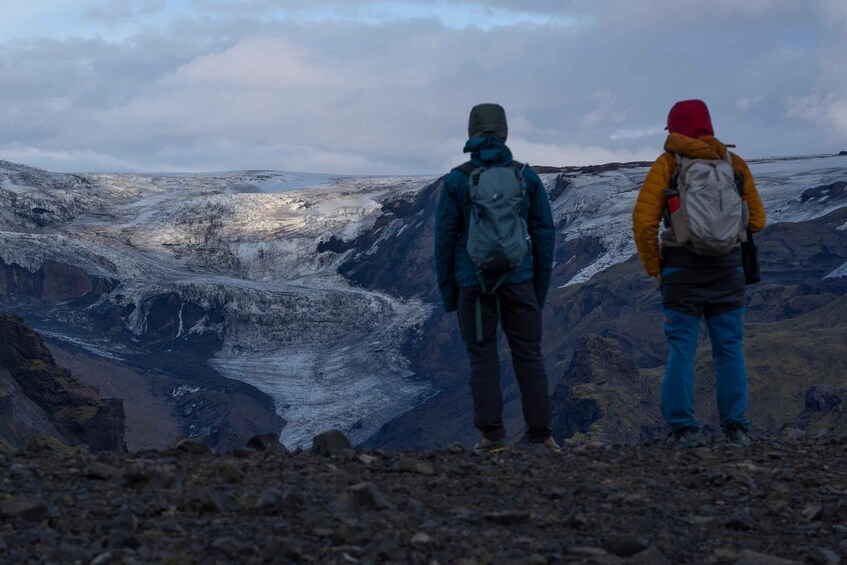Two hikers on a rocky mountain with a glacier in the background. 2