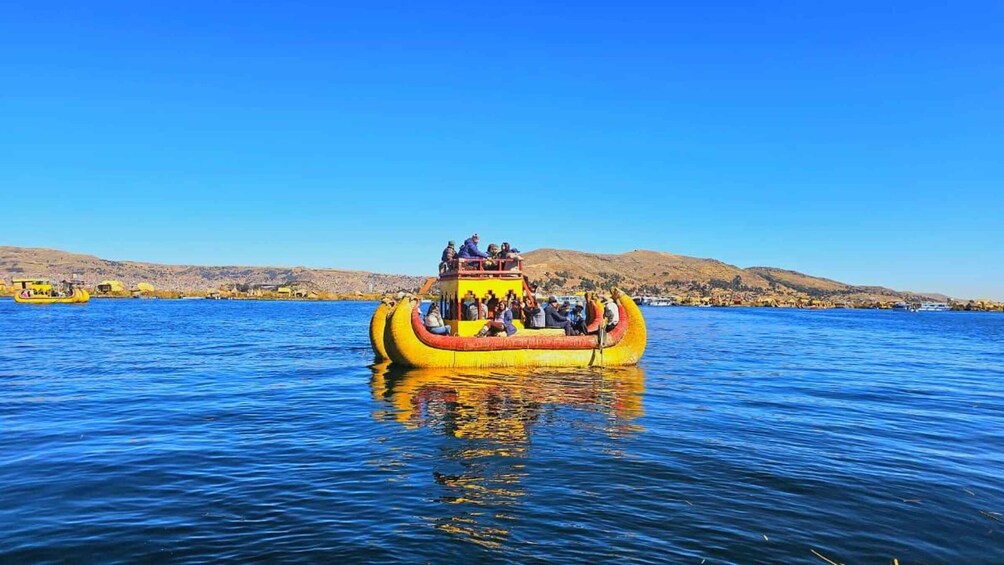 A yellow boat with passengers on a calm lake, surrounded by hills. 5