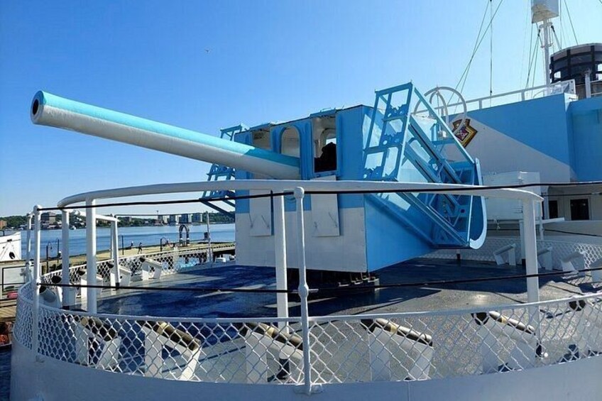 A ship's deck with a large gun, a staircase, and a railing. 5