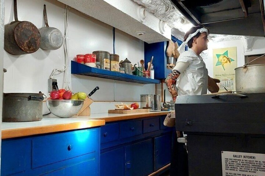 A kitchen with blue cabinets, a metal bowl of fruit, and a person cooking. 3