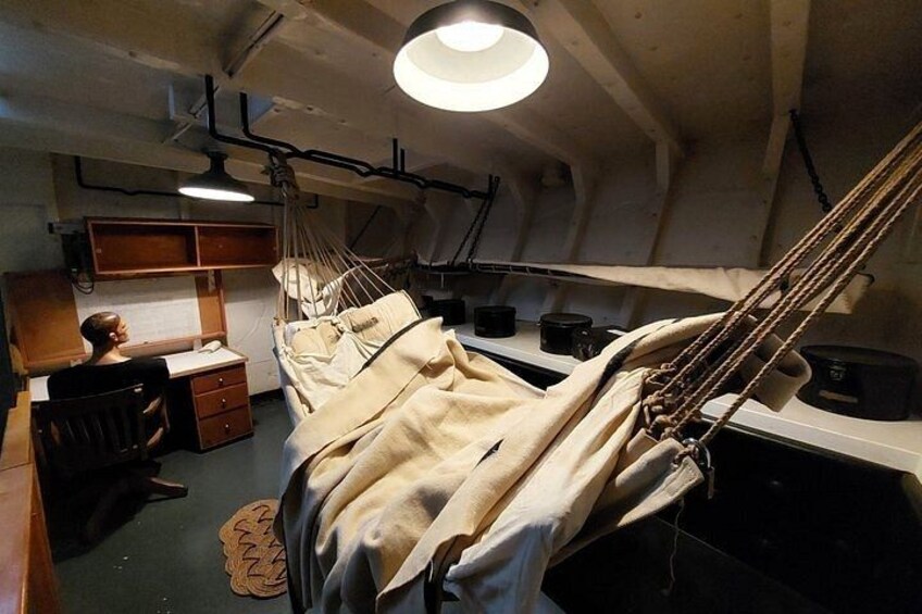A hammock suspended from the ceiling, a desk with a chair, and a bed with a blanket. 4