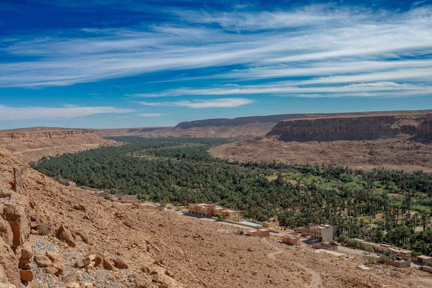 A desert landscape with a small settlement, sparse vegetation, and distant mountains under a clear sky. 3