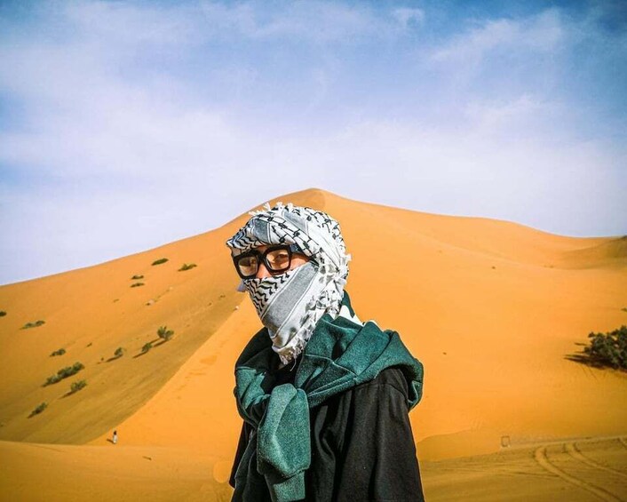 A person standing in a desert with sand dunes in the background. 1
