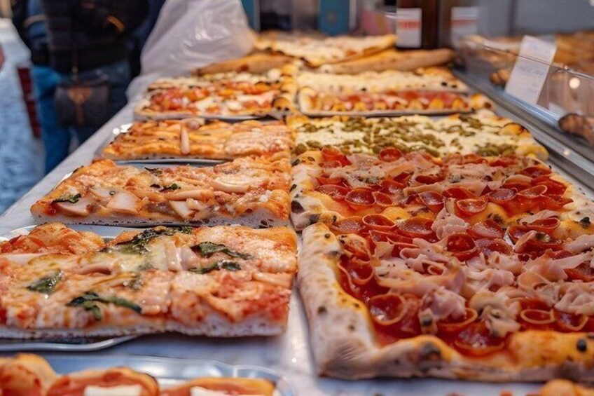 A variety of pizzas with different toppings displayed in a shop. 5