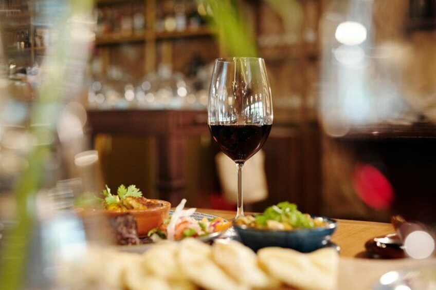 A glass of red wine, a bowl of salad, and a plate of bread on a table. 1
