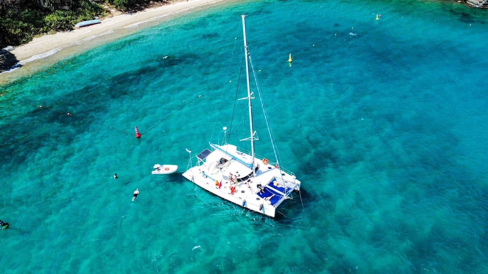 A sailboat anchored in clear turquoise waters near a sandy beach. 1