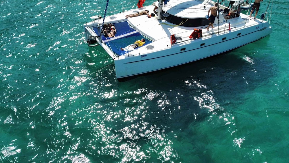 A white yacht with people sunbathing on deck, surrounded by clear turquoise water. 4