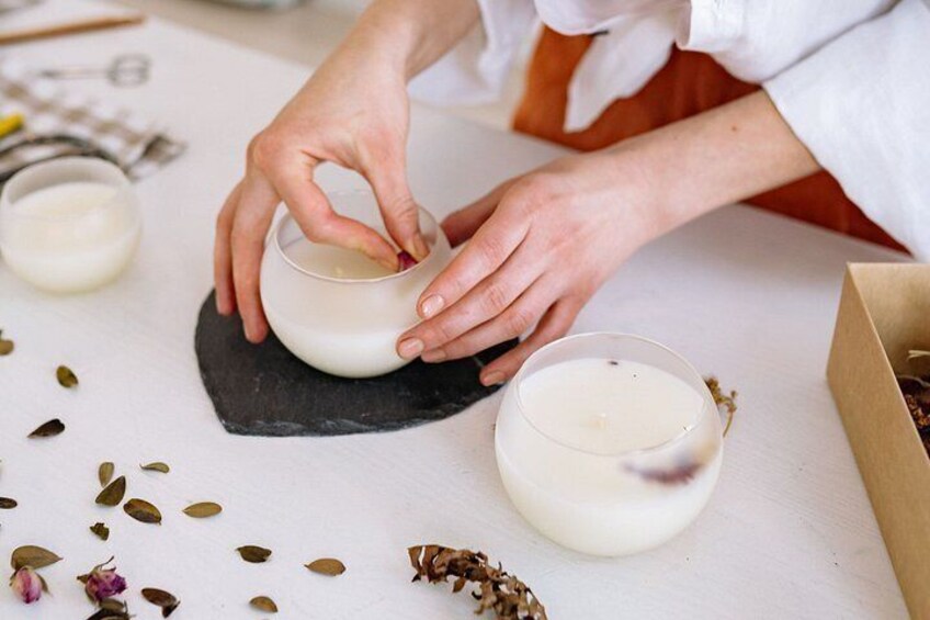 Hands mixing a creamy substance in a small bowl, with a larger bowl and scattered seeds on a white surface. 1