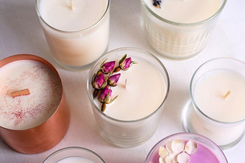 Various candles in different containers, some with flowers and spices. 4