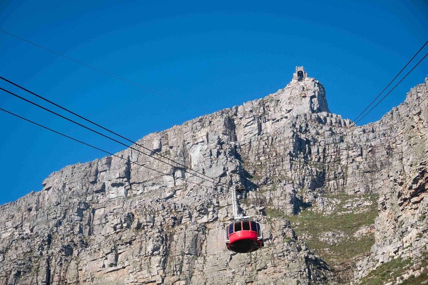 Eine rote Seilbahn fährt einen felsigen Berg hinauf. 1