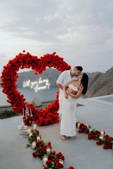 A couple kissing in front of a heart-shaped floral arrangement with a 'Will you be my forever?' sign. 4