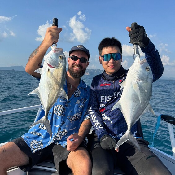 Two people on a boat holding fish. 4