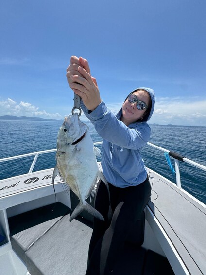 A person holding a fish on a boat with a clear sky and water in the background. 3