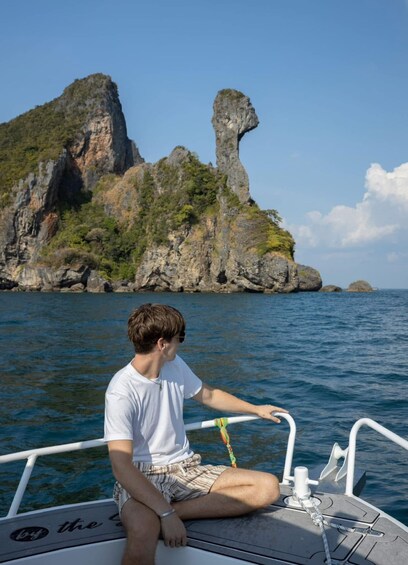 A person on a boat with a rocky island and clear blue water in the background. 2