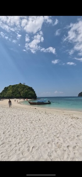A sandy beach with a boat, a small island, and a clear blue sky. 5