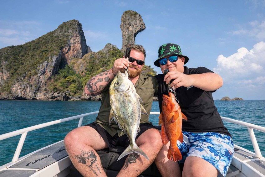 Two people on a boat holding fish, with a rocky island in the background. 1