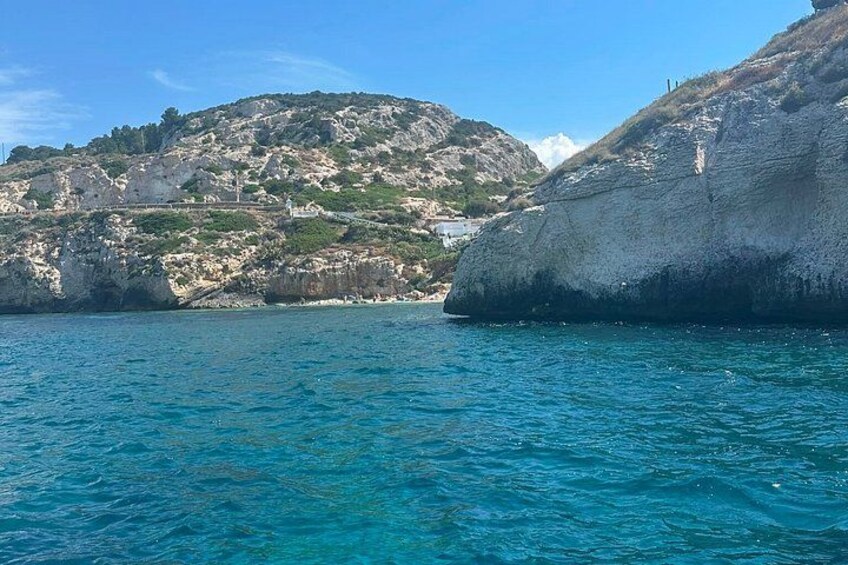 A coastal landscape with rocky cliffs and clear blue waters. 4