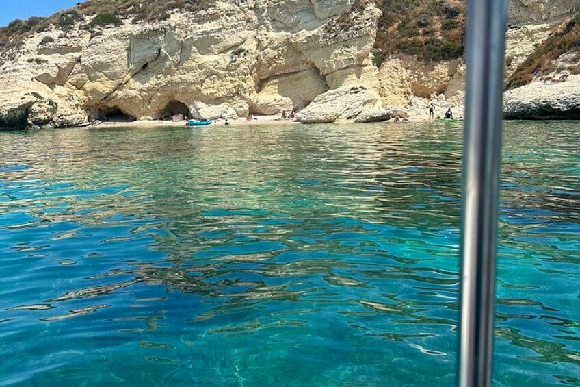 Clear blue water, rocky cliffs, and a boat. 5