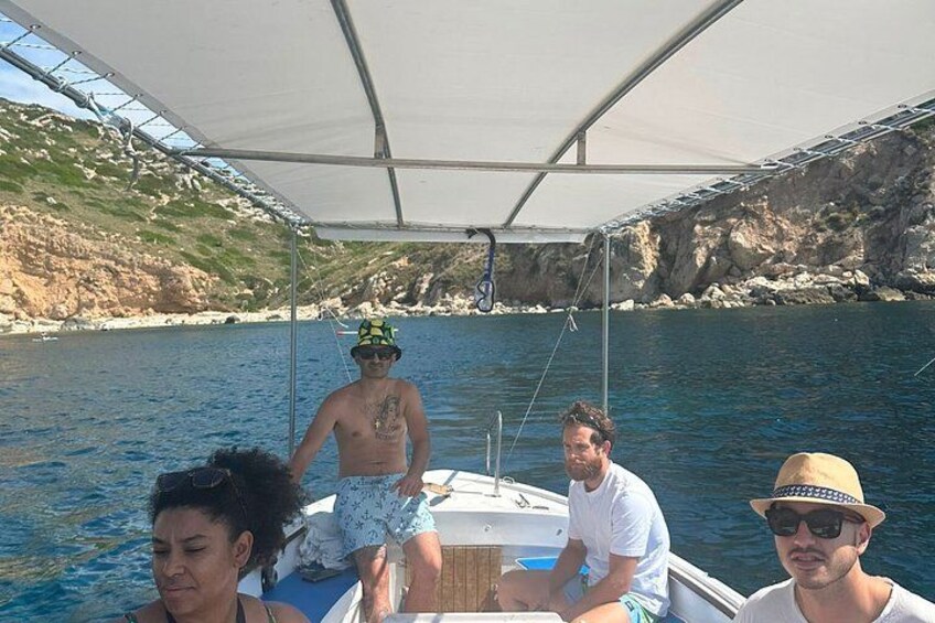 A boat with people on it, a rocky coastline, and clear blue water. 3