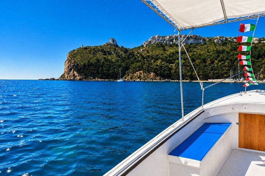 A boat on calm blue waters with a mountainous coastline in the background. 1