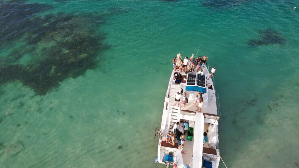 A boat with people on deck, surrounded by clear turquoise water. 3