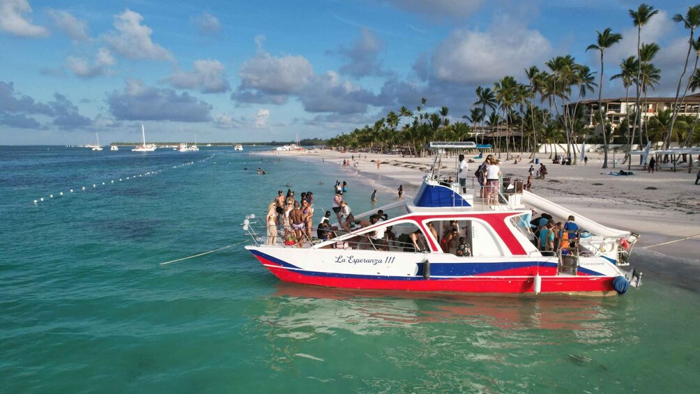 A boat named 'La Esperanza 111' on calm turquoise waters near a sandy beach with palm trees and a clear sky. 2