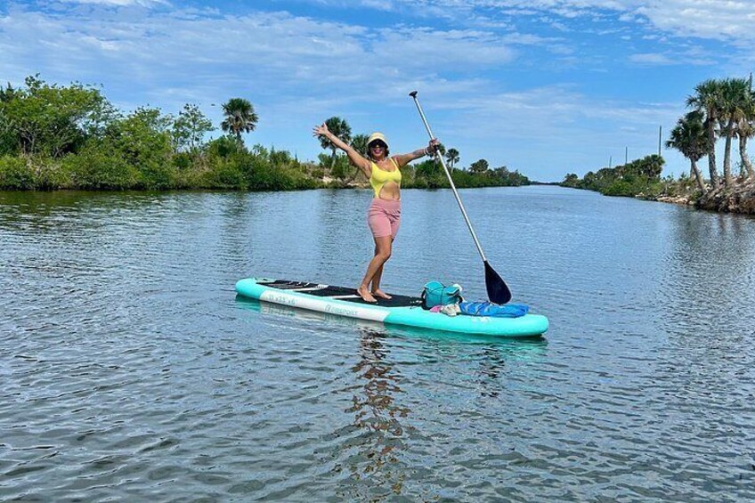 A person paddleboarding on a calm river surrounded by greenery. 5