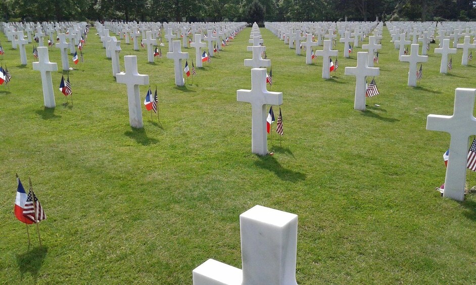 A cemetery with rows of white crosses and American and French flags. 4