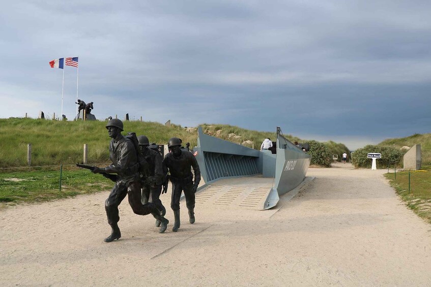 A military statue, a flag, and a pathway leading to a building. 1