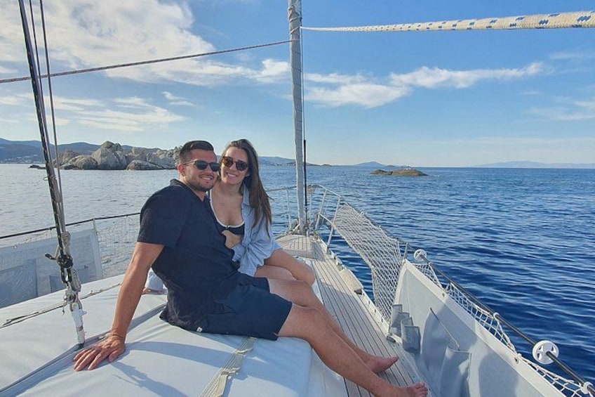 A couple on a sailboat with a clear view of the sea and distant land. 3