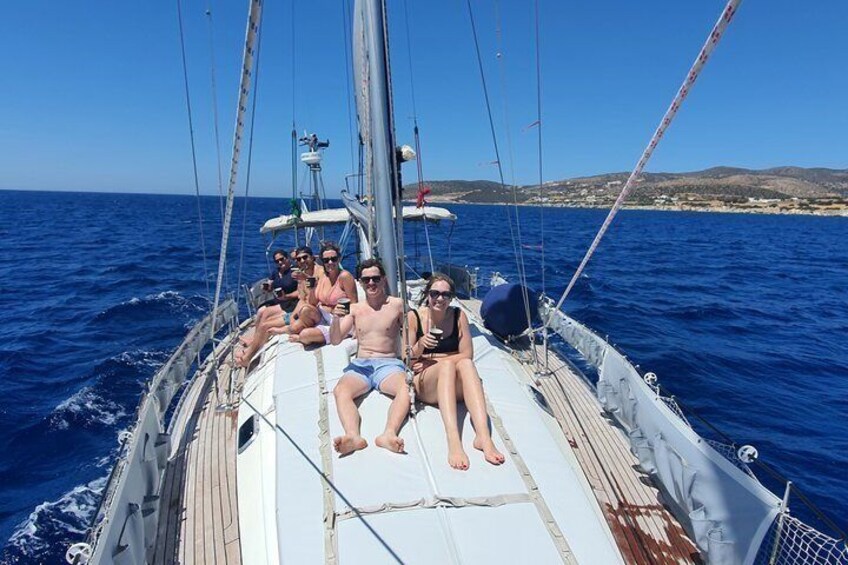 A sailboat with passengers on deck, surrounded by blue water and a distant shoreline. 4